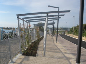 foto di un percorso pedonale con tettoia frangisole e piante rampicanti