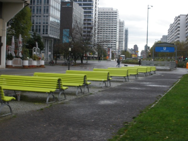 Foto con una serie di panchine con schienale, di colore verde.